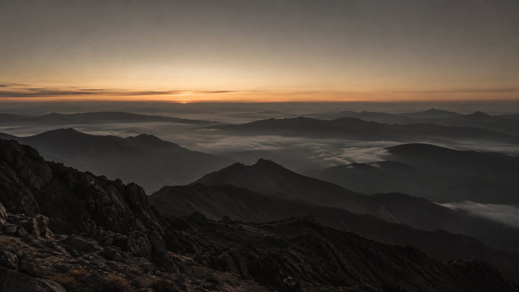 A quiet mountain horizon with a thin line of dawn light.